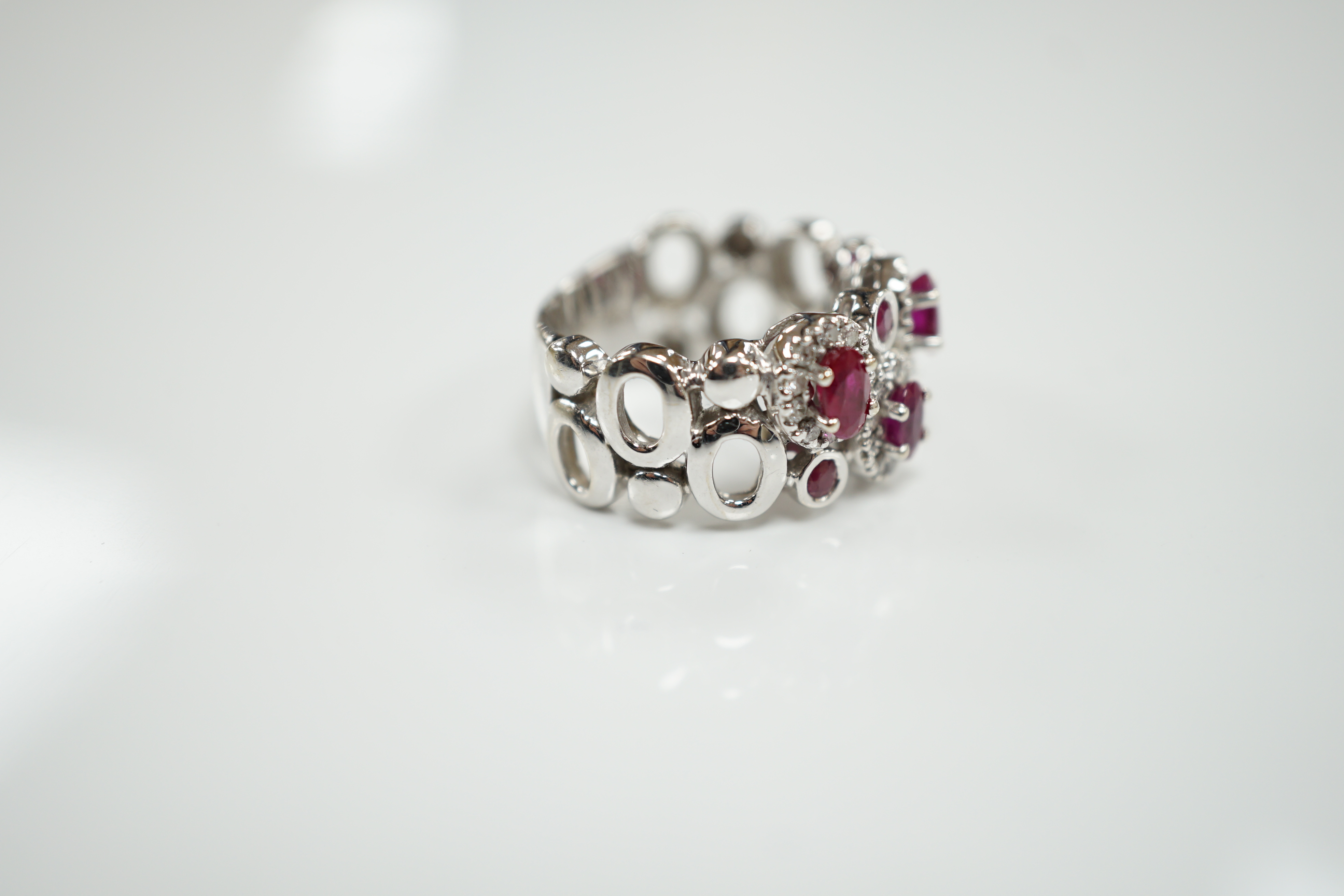 A modern 14ct white gold, ruby and diamond set multi cluster half hoop dress ring, size O, gross weight 8.1 grams.